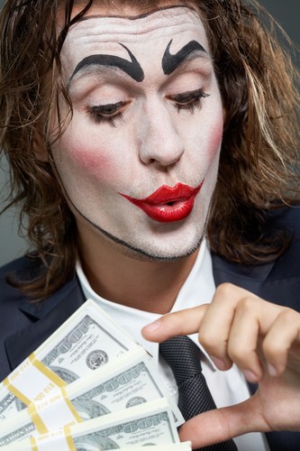 Business man with clown face counting money symbolic of Inbox Dollars unethical business practices.